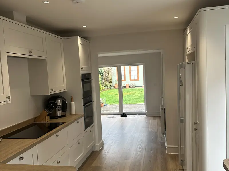 Completed kitchen and dining space with a flush ceiling and recessed downlights