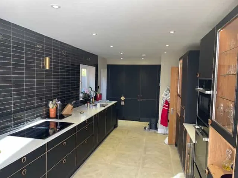 Contemporary fitted kitchen with dark units and integrated appliances